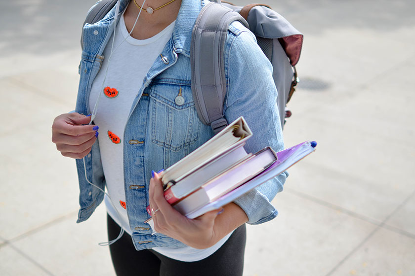 skolungdom som bär på ryggsäck och böcker