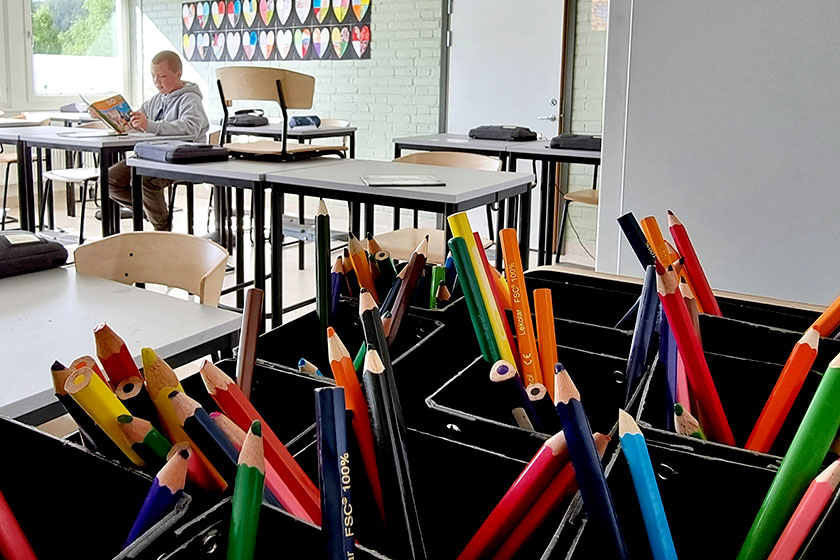 Pojke i klassrum, pennor i förgrunden