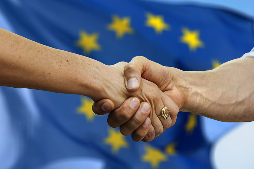 två som skakar hand, EU-flagga i bakgrunden